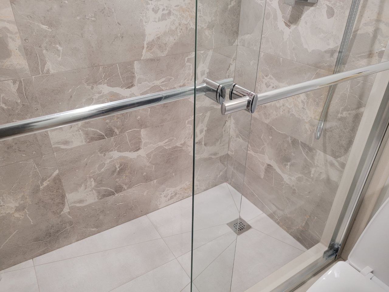 Glass shower enclosure with marble tile