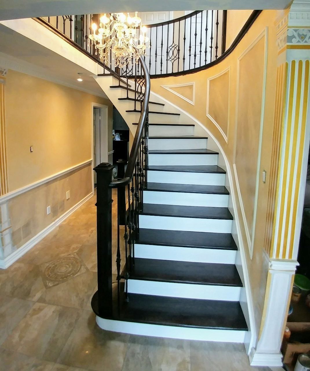 Curved staircase with dark stained treads and iron railing
